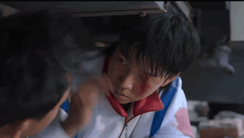 a boy with blood on his face is being helped by a man