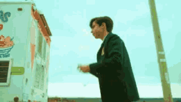 a man in a suit is standing in front of a ice cream truck .