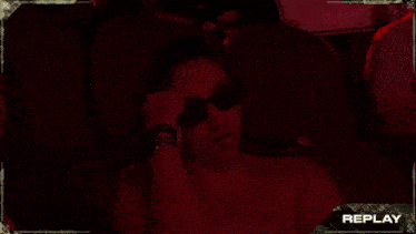 a woman in a dark room with replay written on the bottom right