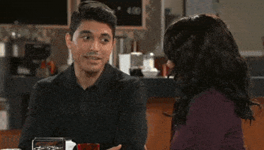 a man and woman are sitting at a table with a sign that says 4.00 in the background
