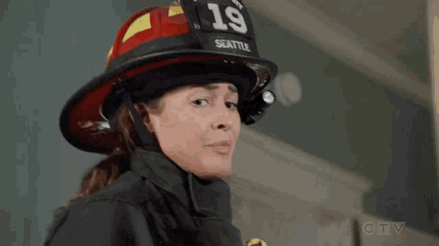 a woman wearing a firefighter 's helmet with the number 19 on it