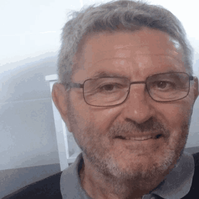a man with glasses and a beard is smiling