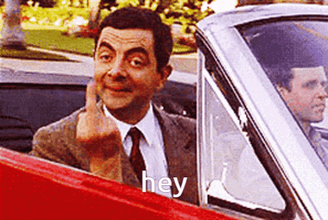 a man in a suit and tie is giving the middle finger and saying hey .