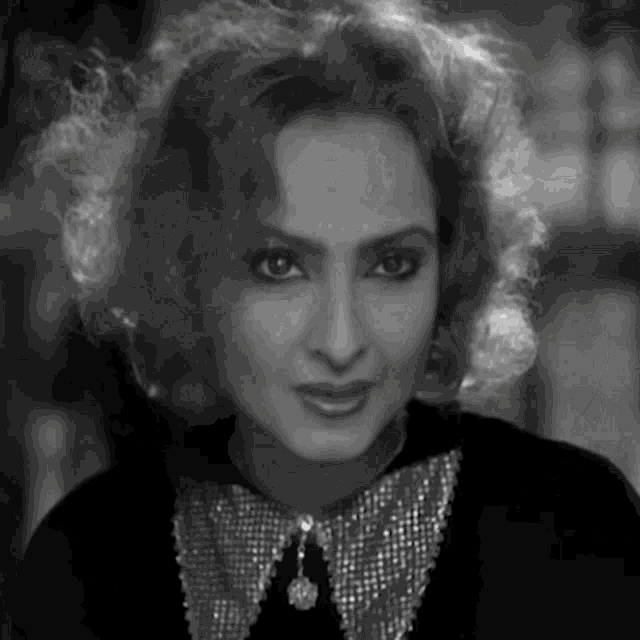 a black and white photo of a woman with curly hair wearing a collared shirt .