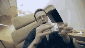 a man in a suit and tie is sitting in a chair holding a stack of money in his hands .