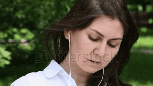 a woman wearing ear buds looks down at something