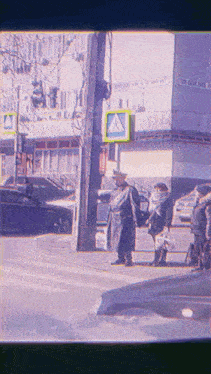a man in a black coat stands in front of a crosswalk sign that says a on it