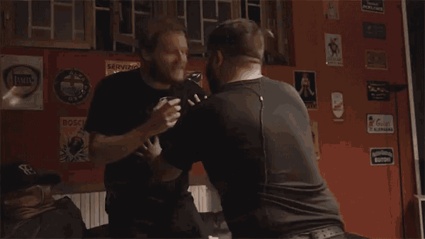 two men are fighting in front of a wall with a sign that says bosch on it
