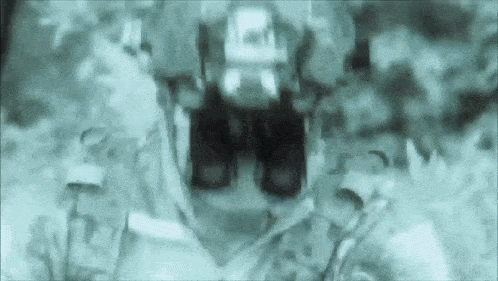 a blurry picture of a tractor driving down a dirt road in the woods .