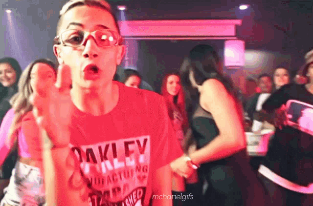 a man wearing an oakley shirt is dancing in a crowd