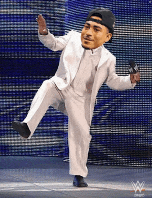 a man in a white suit and black hat holds a microphone with a w logo on it