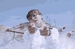 a young man wearing glasses and a white shirt is making a peace sign .