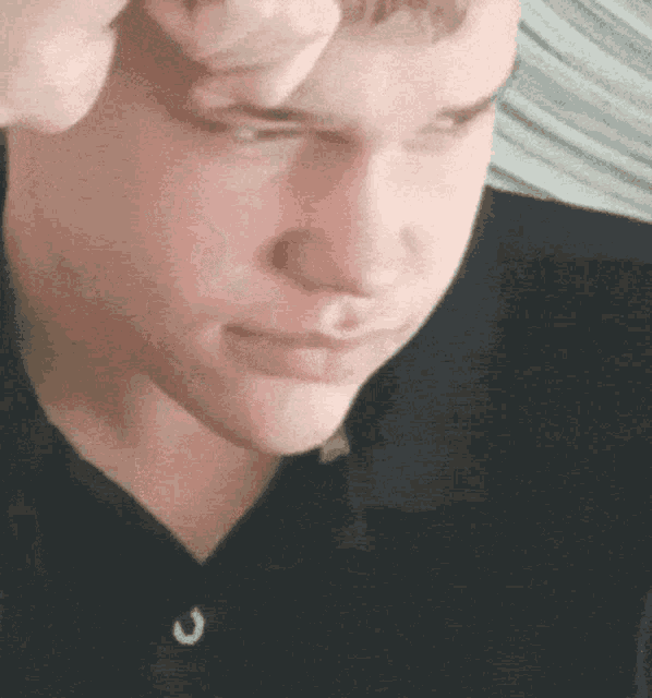 a close up of a man 's face with his eyes closed and his hand on his head .