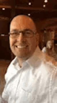 a man wearing glasses and a white shirt is smiling for a picture .