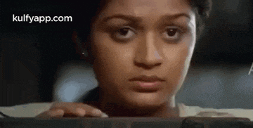 a woman is looking at the camera while typing on a computer keyboard .