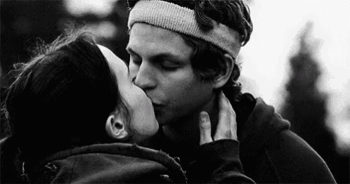 a man and woman are kissing in a black and white photo .
