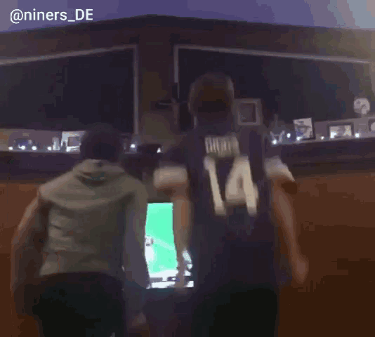 a man with the number 14 on his back stands in front of a television