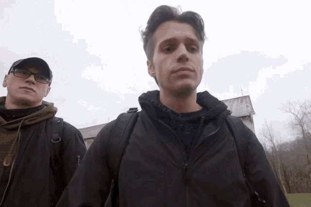 two men standing next to each other with one wearing a black jacket that says nike on it