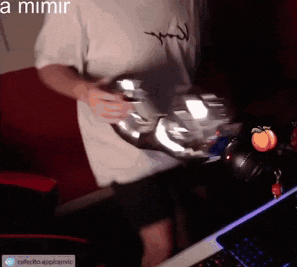 a man in a white shirt is holding a silver object in front of a computer .