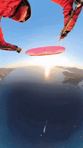 a person in a red jacket is flying through the air with a pink parachute