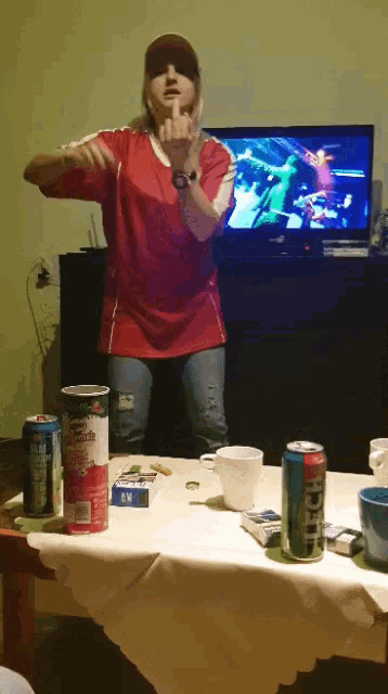 a woman in a red shirt giving the middle finger in front of a tv