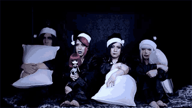 a group of people are laying on a bed holding pillows and wearing santa hats