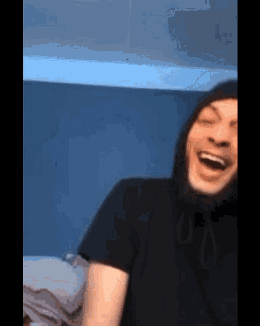 a man wearing a black shirt and a hooded hat is laughing .