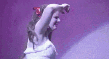 a woman in a white dress is dancing on a stage .