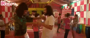 a group of people are dancing together in a room with checkered walls .