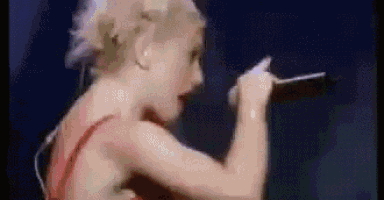 a woman in a red dress is singing into a microphone on stage .