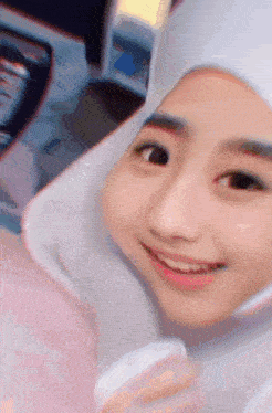 a girl wearing a hijab is smiling for the camera