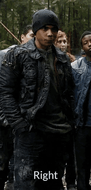 a man in a black jacket stands in front of a group of people with the words right below him