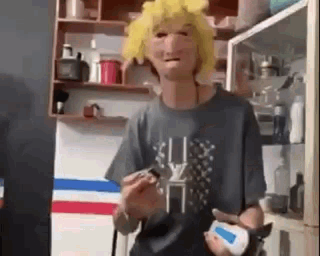 a man wearing a yellow wig and a mask is holding a shaving razor in a bathroom .