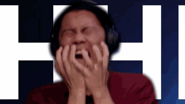 a man wearing headphones covers his mouth with his hands