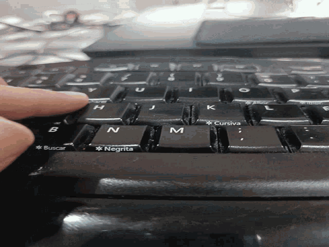 a person is typing on a black keyboard with the letters n and m on it