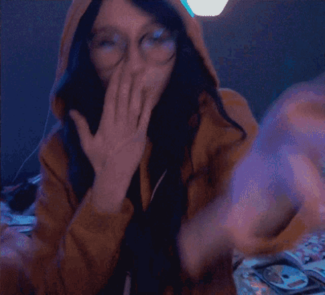 a woman wearing glasses and a hoodie is making a hand gesture