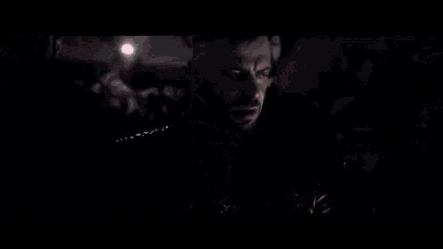 a man with a beard is wearing a black leather jacket and a necklace with a skull pendant .