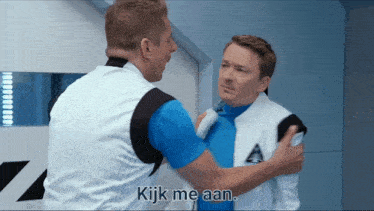 a man in a blue shirt is hugging another man in a white vest with the words " kijk me aan " below him