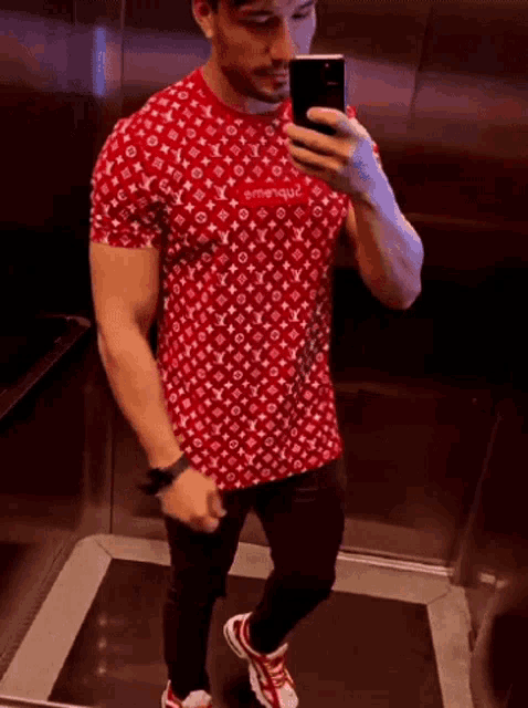 a man is taking a picture of himself in an elevator wearing a supreme shirt