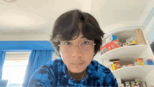 a young man wearing glasses and headphones looks at the camera .