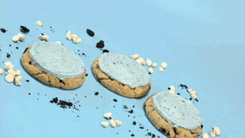 a person wearing black gloves is holding a cookie with frosting