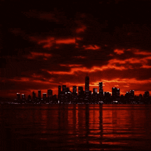 a city skyline silhouetted against a red cloudy sky at sunset