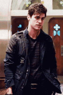 a young man wearing a black leather jacket stands in front of a church door