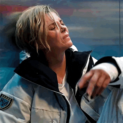 a woman in a white jacket is sitting down with her eyes closed and a bandage on her hand .