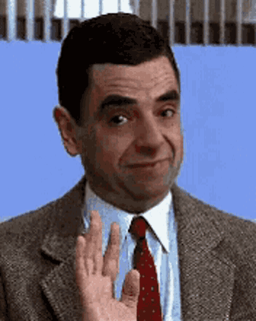 a man in a suit and tie is waving