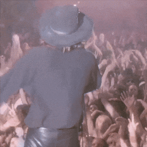a man in a cowboy hat is singing into a microphone in front of a crowd