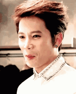 a close up of a young man wearing a white shirt and earrings