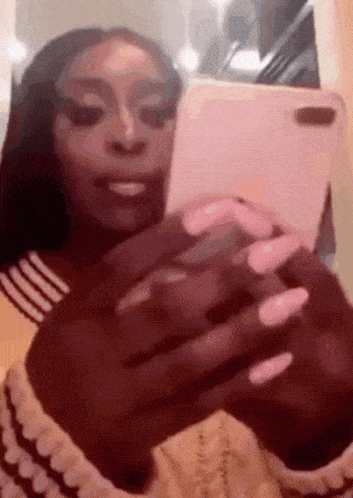a woman with long nails is taking a selfie with her phone .