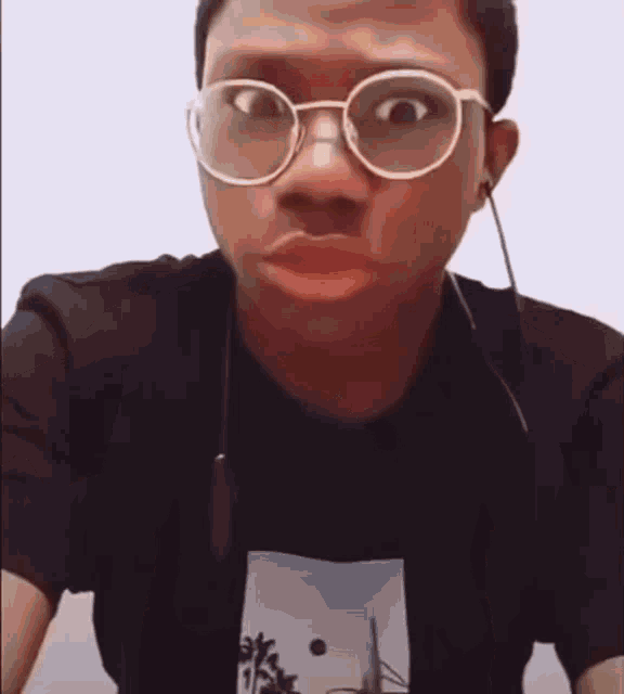 a man wearing glasses and ear buds is making a funny face .
