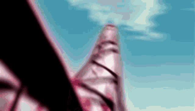 a close up of a person holding a sword in front of a blue sky with clouds .